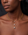 Diamond carat size comparison on a model's neck, showing 1-carat, 2-carat, and 3-carat round stones on a delicate three-tier layered gold chain necklace.