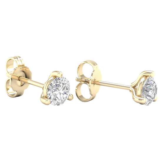 A pair of yellow gold stud earrings, each featuring a single brilliant-cut diamond held in a three-prong setting, displayed against a dark, transparent checkerboard background.