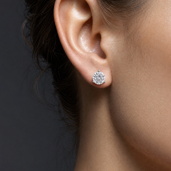Profile view of a woman's ear wearing a round diamond stud earring.