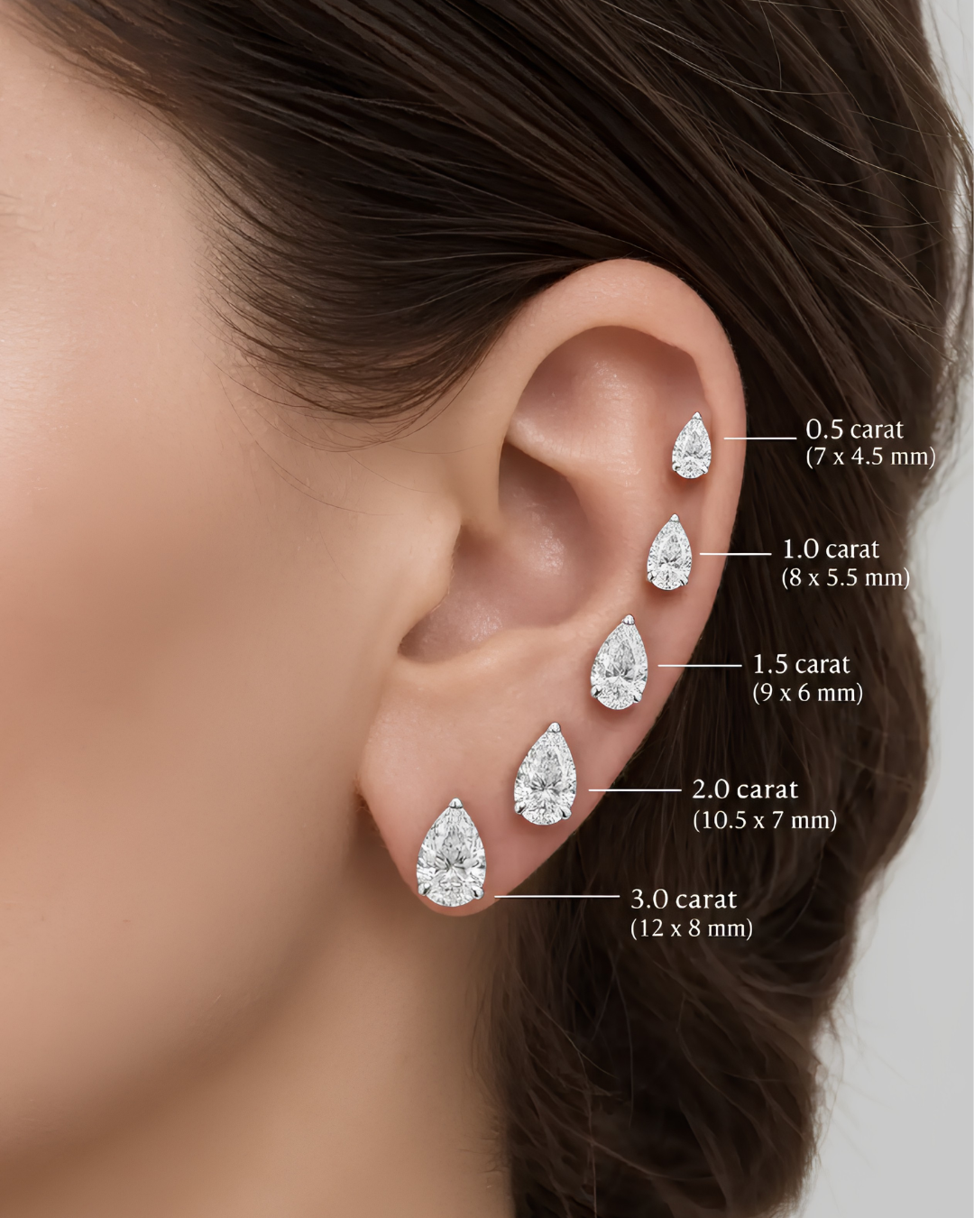 Amorati Diamonds womens ear with 5 pear cut diamonds .5, 1, 1.5, 2, 3 carats up the ear to show the size difference.