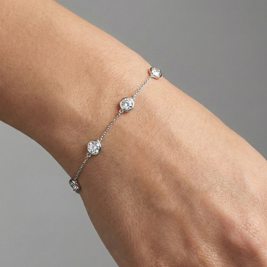 A full top-down view of a 14K white gold bracelet, showing the spaced-out, bezel-set diamonds on the delicate chain on figure.