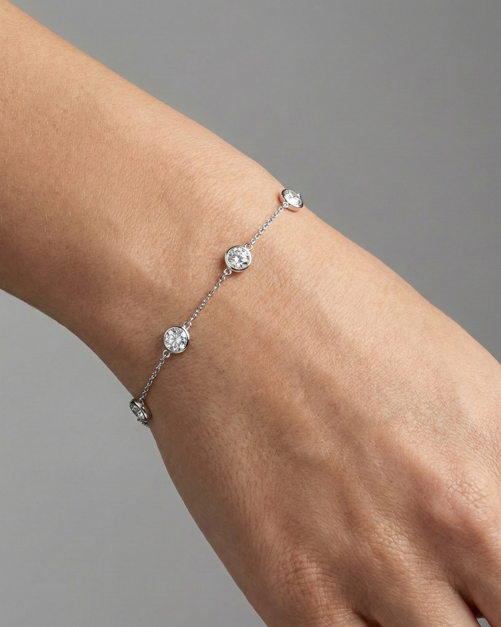 A full top-down view of a 14K white gold bracelet, showing the spaced-out, bezel-set diamonds on the delicate chain on figure.