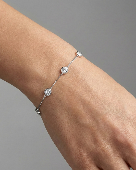 A full top-down view of a 14K white gold bracelet, showing the spaced-out, bezel-set diamonds on the delicate chain on figure.