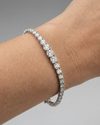 A full top-down view of a 14K white gold tennis bracelet, coiled to show the cascading line of round diamonds and the clasp on wrist.