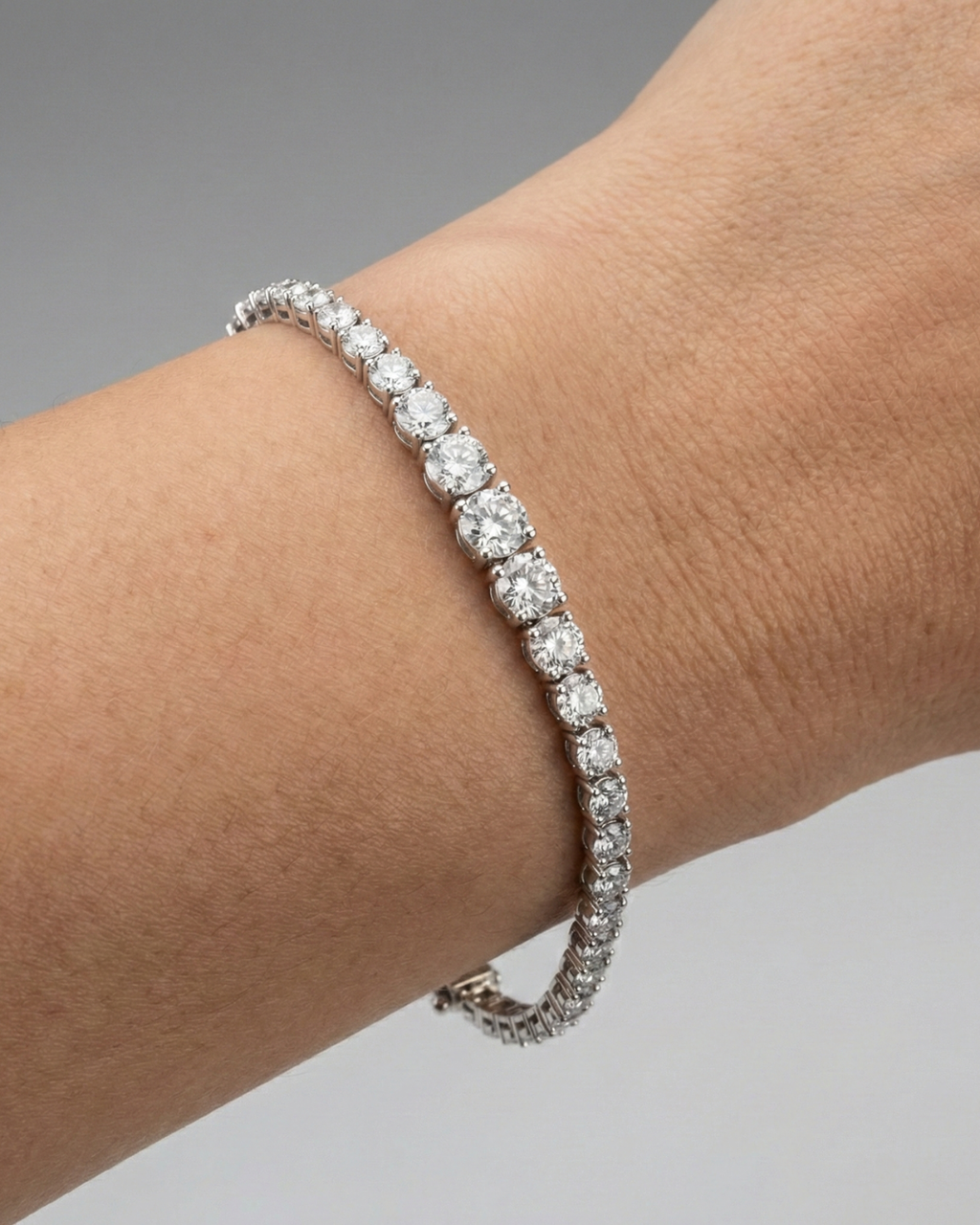 A full top-down view of a 14K white gold tennis bracelet, coiled to show the cascading line of round diamonds and the clasp on wrist.