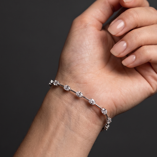 Close-up lifestyle view of a modern 14k white gold or platinum station bracelet featuring horizontally set oval-cut diamonds connected by sleek bar links on a wrist.