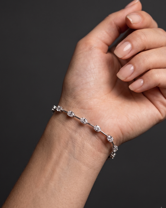 Close-up lifestyle view of a modern 14k white gold or platinum station bracelet featuring horizontally set oval-cut diamonds connected by sleek bar links on a wrist.
