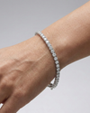 A full top-down view of a 14K white gold tennis bracelet, coiled to show the seamless, continuous line of round diamonds on wrist.