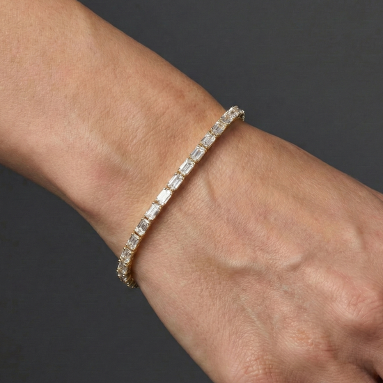 Lifestyle view of a yellow gold diamond tennis bracelet worn on the wrist, showcasing emerald cut diamonds in a refined fine jewelry design.