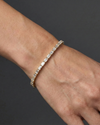 Lifestyle view of a yellow gold diamond tennis bracelet worn on the wrist, showcasing emerald cut diamonds in a refined fine jewelry design.