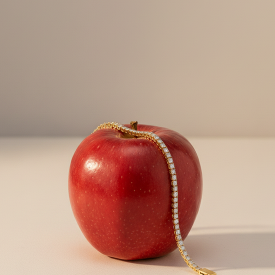 A view of the 14K yellow gold tennis bracelet, coiled to show the continuous, brilliant line of diamonds on a red apple.