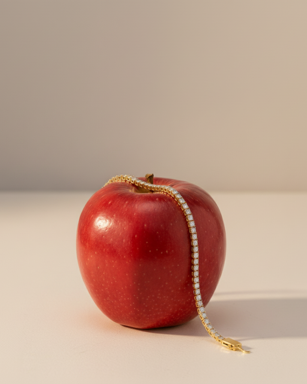A view of the 14K yellow gold tennis bracelet, coiled to show the continuous, brilliant line of diamonds on a red apple.