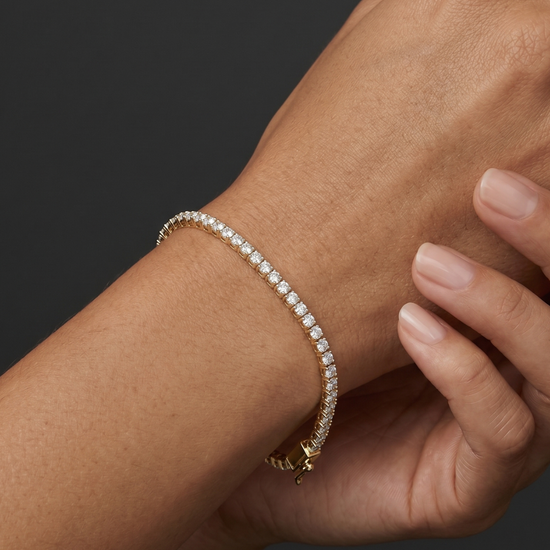 Close-up lifestyle view of a classic 14k rose gold tennis bracelet featuring a continuous, uniform row of brilliant round-cut diamonds styled on a wrist.