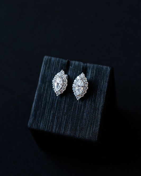 White gold Amorati Enchanted Marquise Stud Earrings displayed on top of a textured black jewelry box against a dark background.