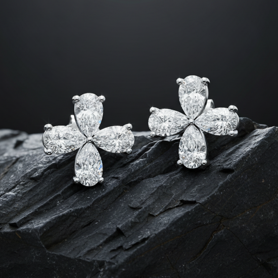 Two diamond flower studs are resting on a textured, dark gray rock to highlight their sparkle.