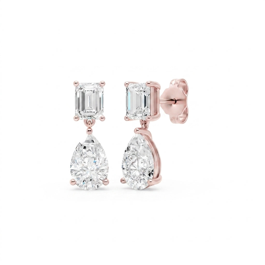 Amorati Diamonds Emerald and Pear Diamond Drop Earrings in 14K Rose gold. these drop stud earrings featuring an emerald-cut clear gemstone in the top and a pear-cut clear gemstone in the bottom, shown on a solid white background.