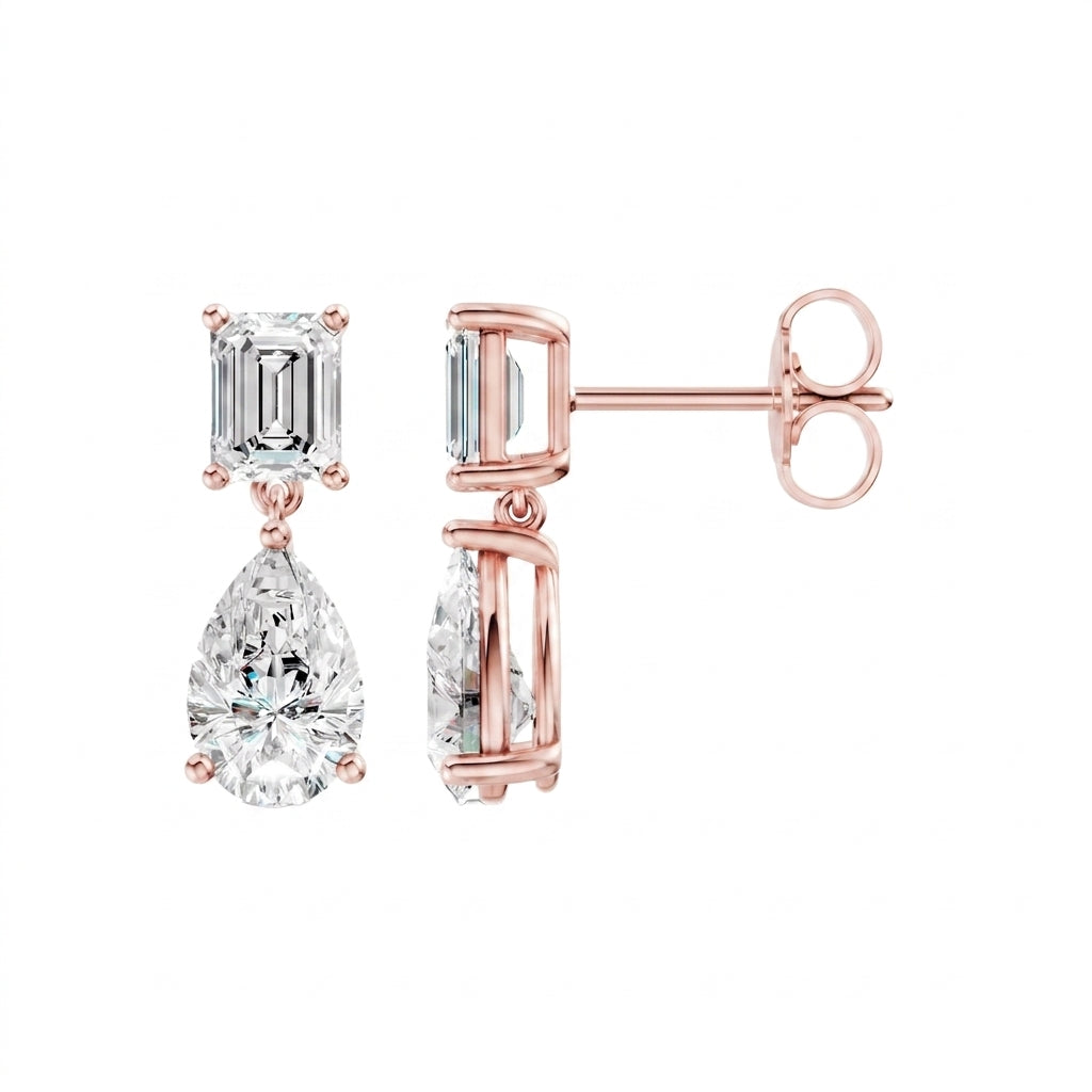 Amorati Diamonds Emerald and Pear Diamond Drop Earrings in 14K Rose gold. these drop stud earrings featuring an emerald-cut clear gemstone in the top and a pear-cut.  shown on a plain white background with one earring facing forward and the other angled to show the post and backing.
