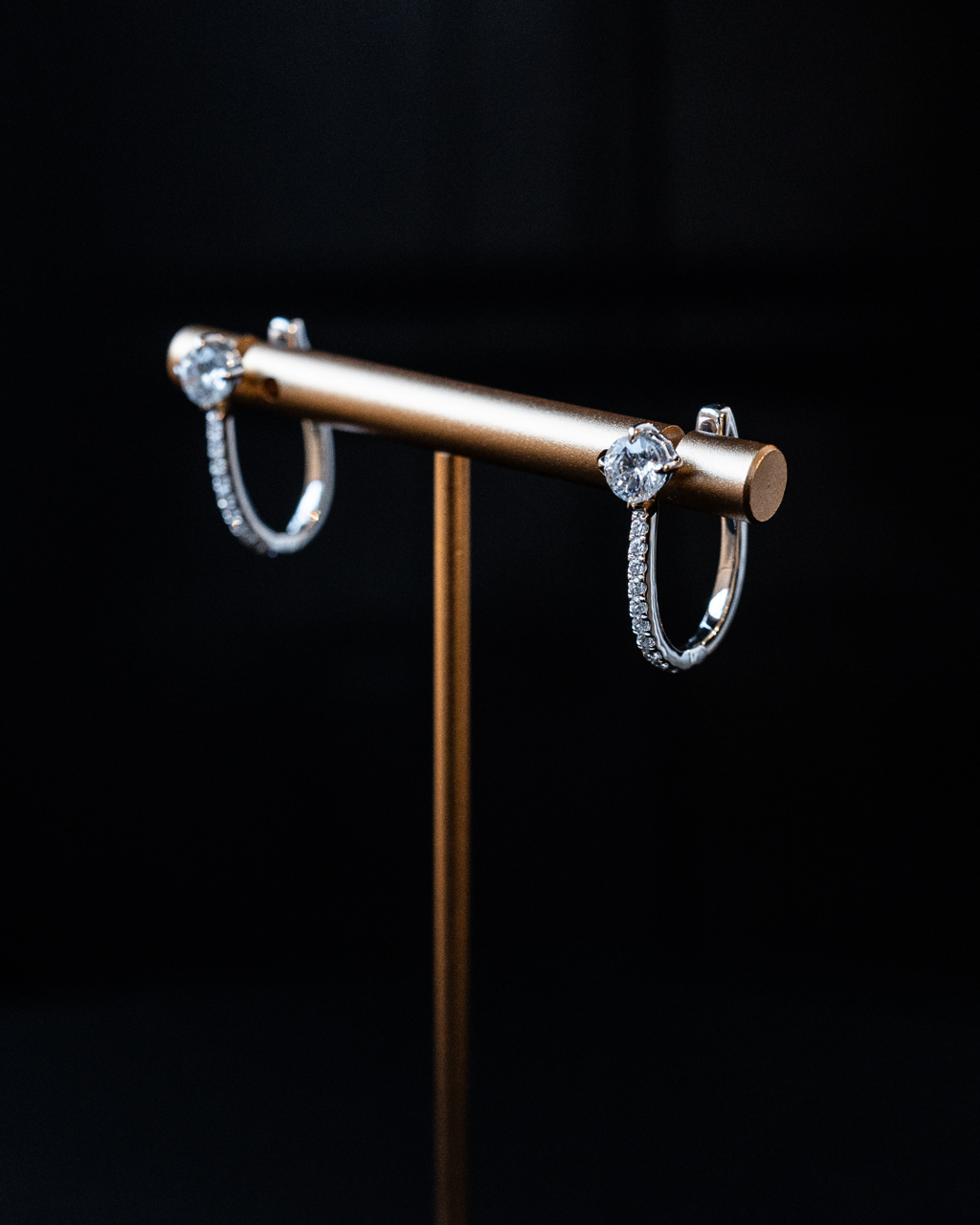 White gold Amorati cascade drop diamond hoop earrings displayed on a gold jewelry stand.