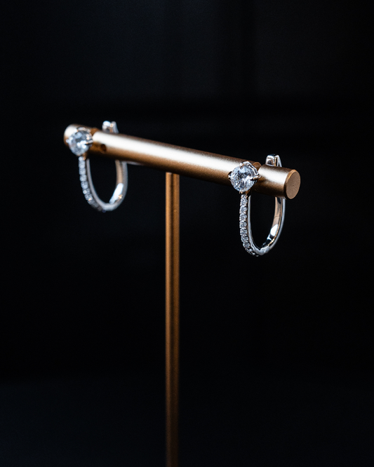 White gold Amorati cascade drop diamond hoop earrings displayed on a gold jewelry stand.