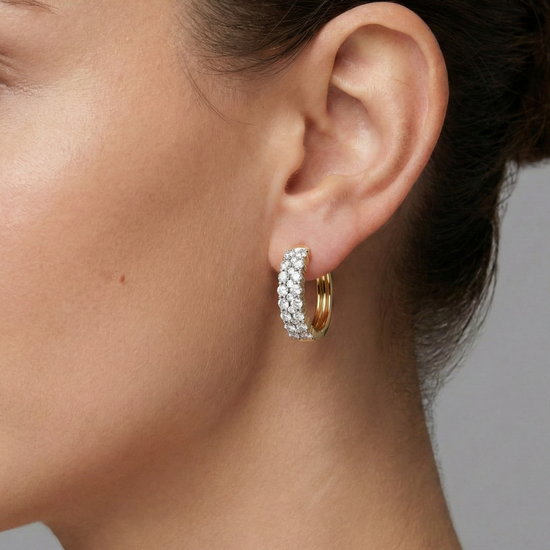 A pair of 14K white gold huggie hoops with two parallel rows of pavé diamonds, shown from the front on ear.