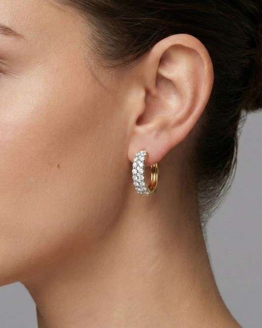 A pair of 14K white gold huggie hoops with two parallel rows of pavé diamonds, shown from the front on ear.