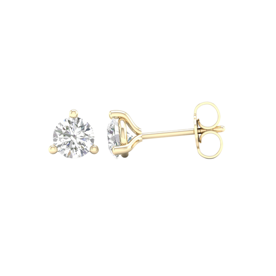 An angled view of a pair of 14K yellow gold three-prong diamond stud earrings, showcasing the full design.