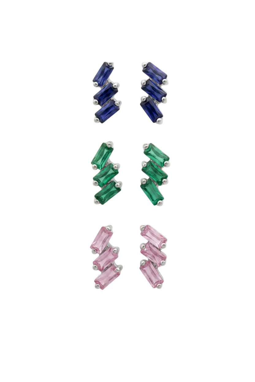 Three colorways in the cascading stud earrings featuring a vertical arrangement of three baguette-cut emerald or pink sapphires or blue sapphire. The rectangular gemstones are staggered in a step-like formation and held in a minimalist 18k white gold setting, shown against a clean, white studio background.