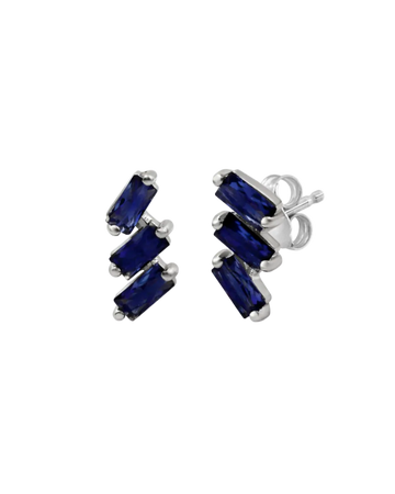 A pair of cascading stud earrings featuring a vertical arrangement of three baguette-cut blue sapphires. The rectangular gemstones are staggered in a step-like formation and held in a minimalist 18k white gold setting, shown against a clean, white studio background.