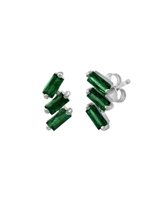 A pair of cascading stud earrings featuring a vertical arrangement of three baguette-cut emeralds in a deep, saturated green. The rectangular gemstones are staggered in a step-like formation and held in a minimalist 18k white gold setting, shown against a clean, white studio background.