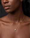 A close-up of a person's lower face and neck wearing a delicate yellow gold chain featuring a small, single round 1-carat diamond pendant resting just below the collarbone.