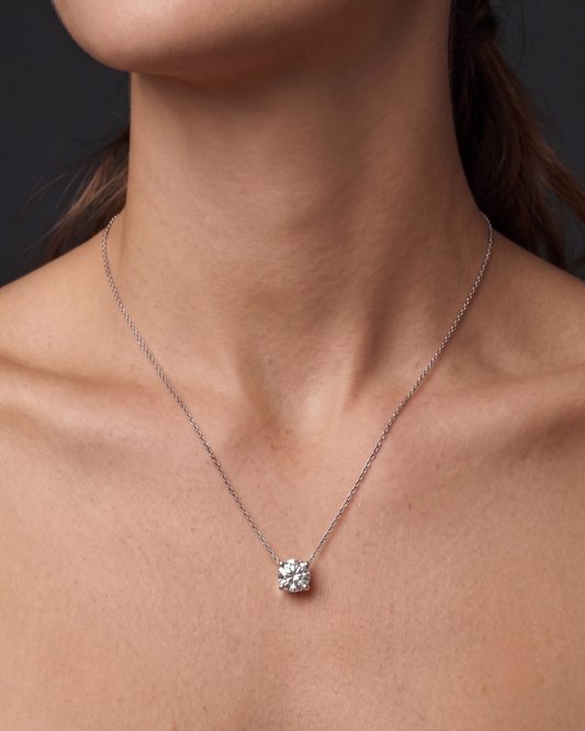 A close-up of a person wearing a delicate white gold chain necklace with a single round diamond pendant 2 carat. 