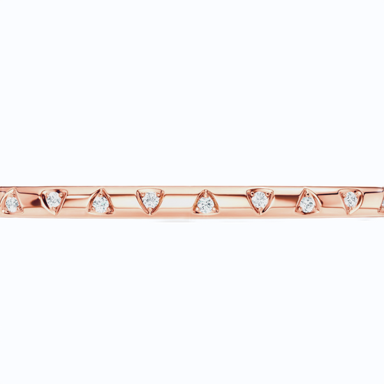 A close-up of the Amorati Diamond Multishape Studded Thin Bangle is a slim 14K rose gold bracelet with a row of stamped shapes inset with round lab grown diamonds on a plain white background.