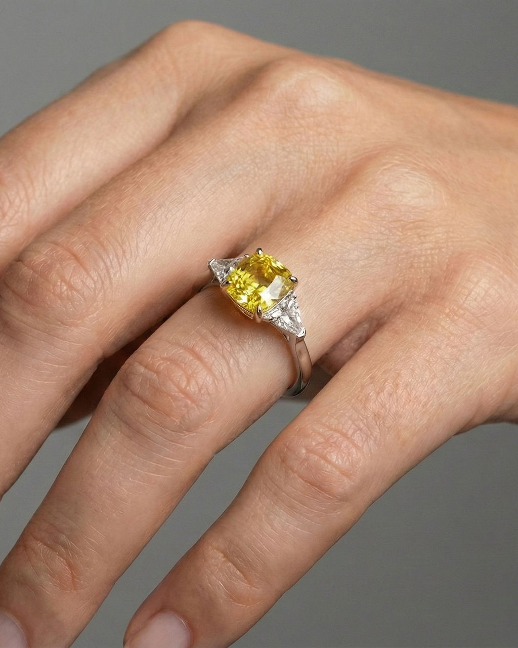 On hand view of the 4.16 Cttw Soleil Cushion Canary Trilogy Diamond Ring with 3.50ct IGI Certified Center Yellow Canary Cushion Stone and an additional .66 cttw Trillion Side Stones