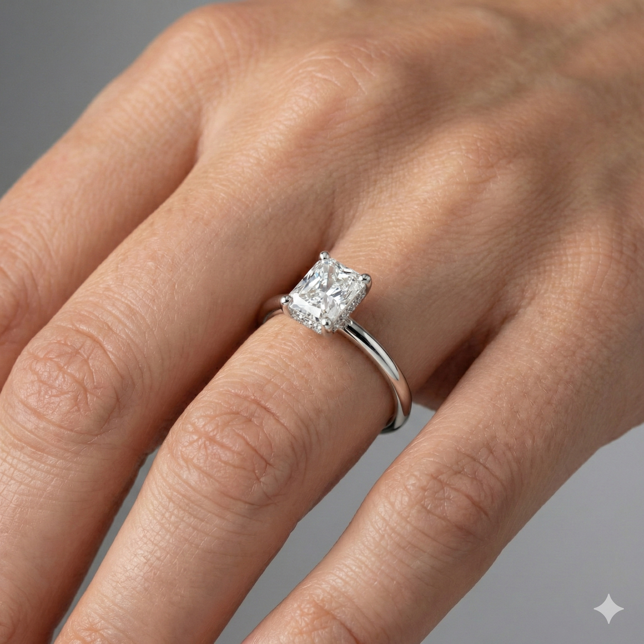 Radiant cut diamond engagement ring in 14k white gold with a plain band and solitaire setting on a hand