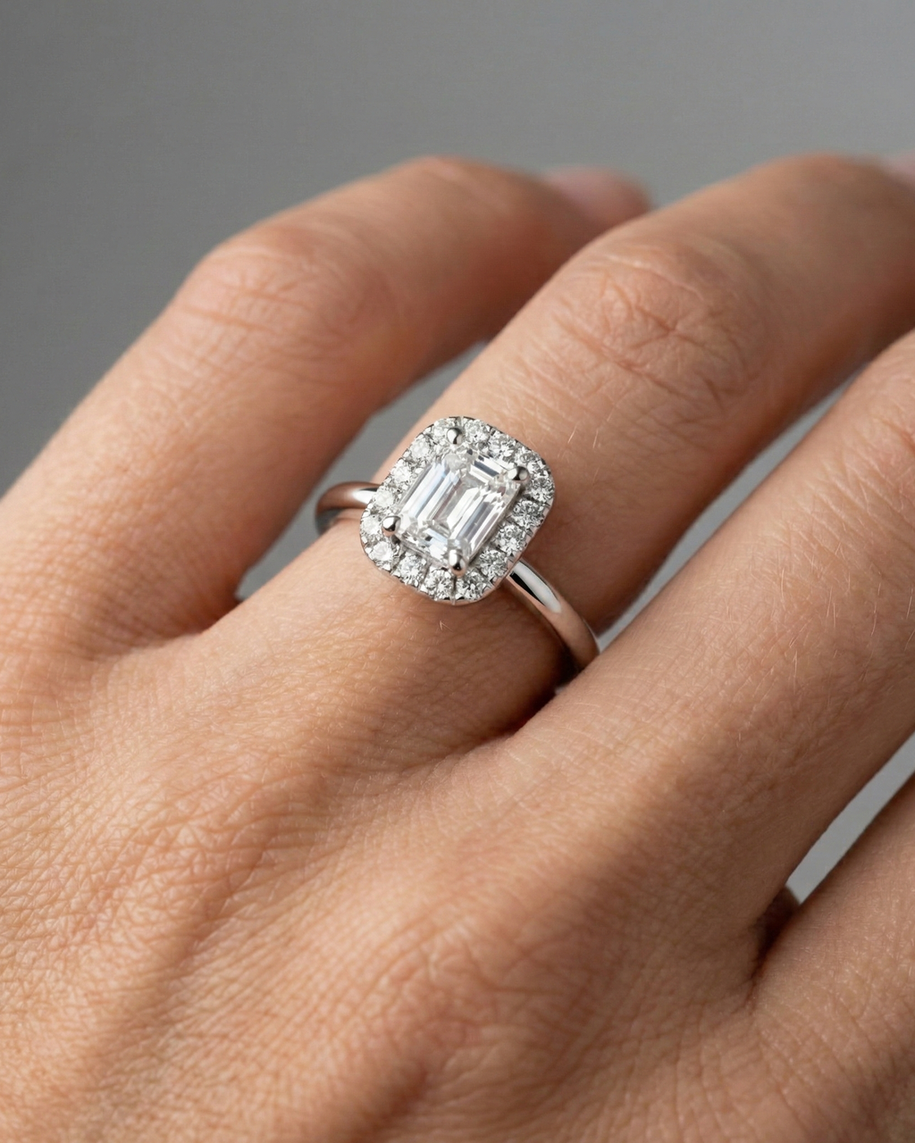 Emerald cut diamond engagement ring in 14k white gold with a plain band and solitaire setting on a hand