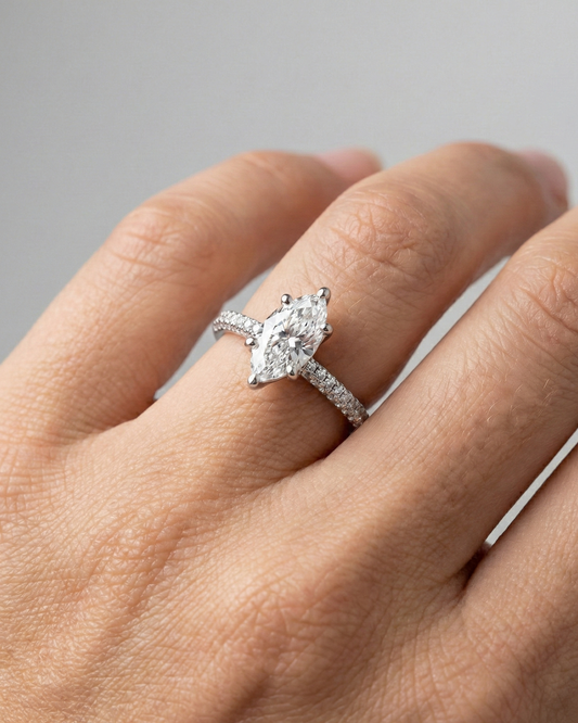 Marquise cut diamond engagement ring in 14k white gold with a pavé diamond band and cathedral setting on a hand