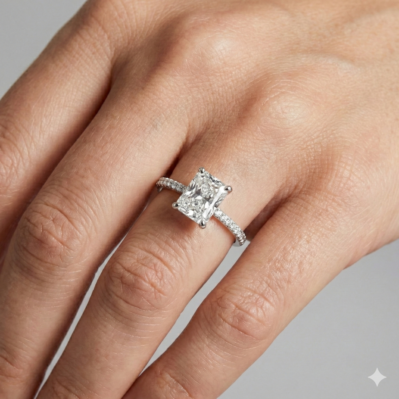Radiant cut diamond engagement ring in 14k white gold with a pavé diamond band and cathedral setting on a hand