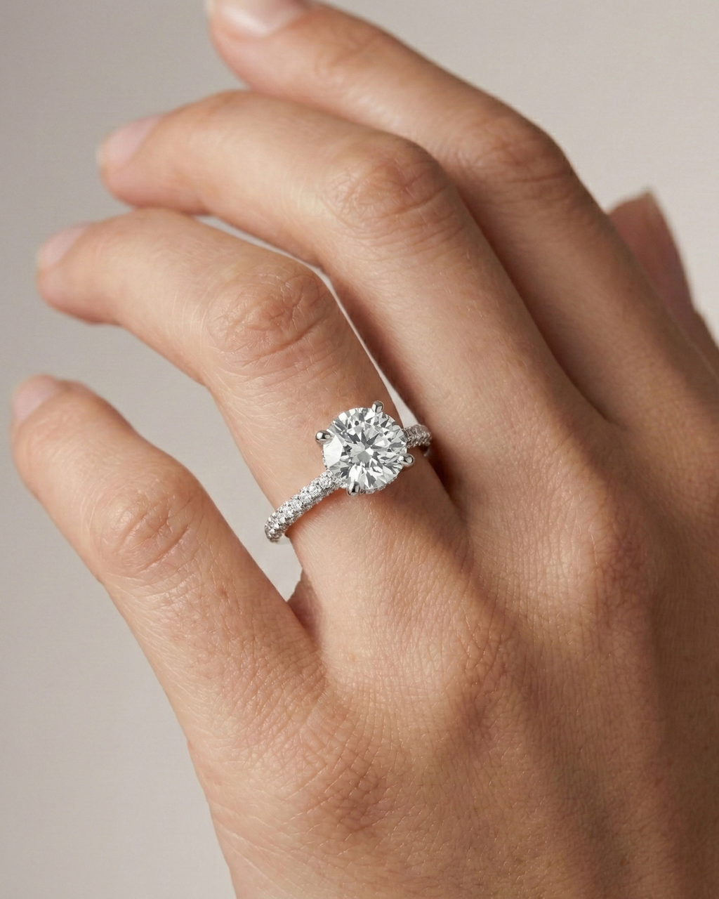 Round cut diamond engagement ring in 14k white gold with a pavé diamond band and cathedral setting on a hand