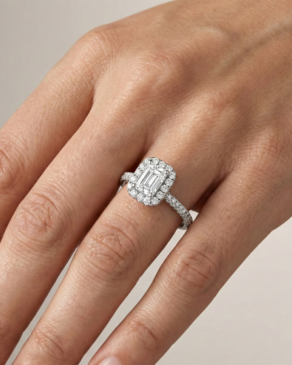 Emerald cut diamond engagement ring in 14k white gold with a pavé diamond band and solitaire setting on a hand