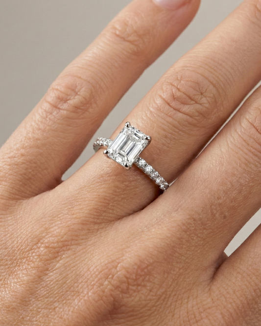 Emerald cut diamond engagement ring in 14k white gold with a prong diamond band and cathedral setting on a hand