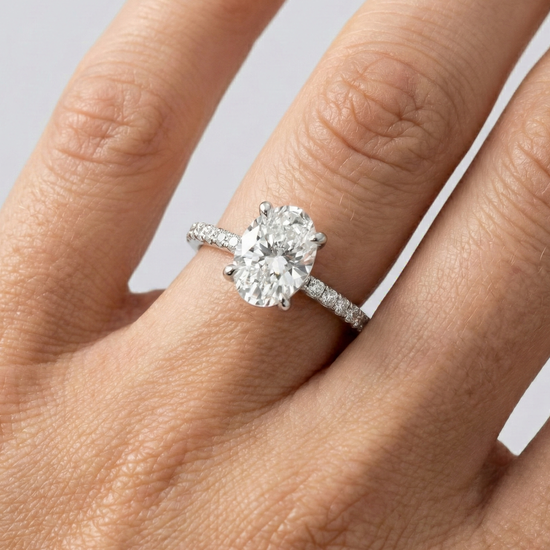 Oval cut diamond engagement ring in 14k white gold with a prong diamond band and cathedral setting on a hand