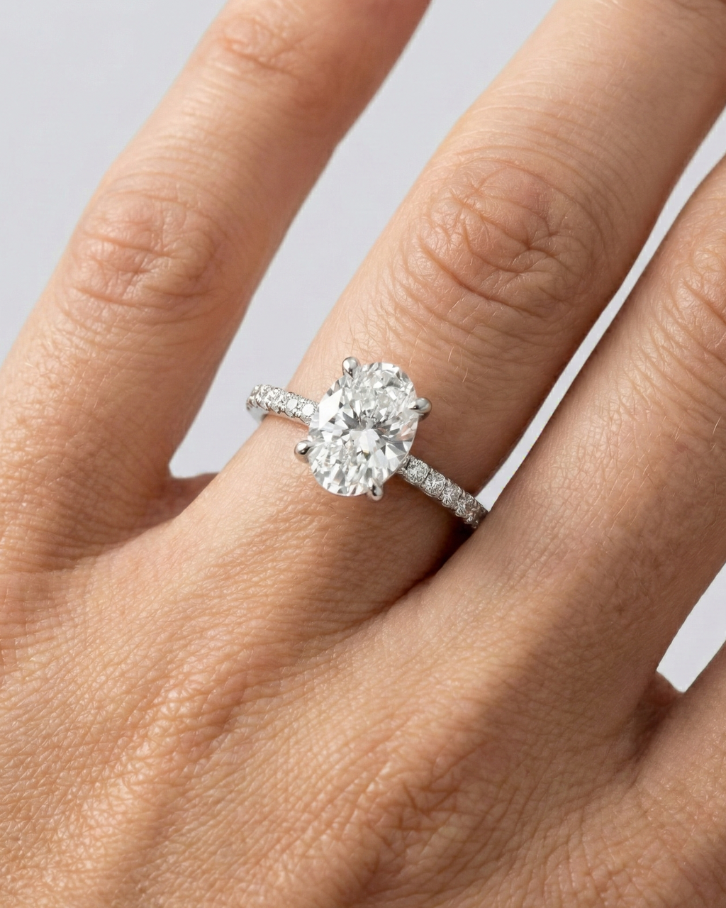 Oval cut diamond engagement ring in 14k white gold with a prong diamond band and cathedral setting on a hand