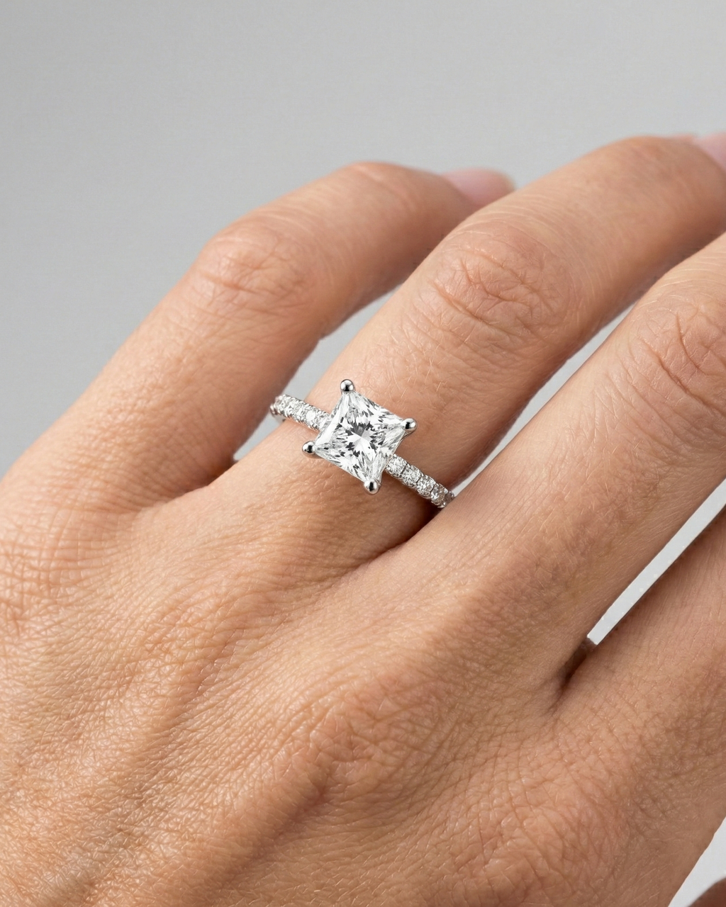 Princess cut diamond engagement ring in 14k white gold with a prong diamond band and cathedral setting on a hand
