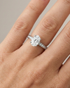 Oval cut diamond engagement ring in 14k white gold with a diamond channel band and cathedral setting on a hand
