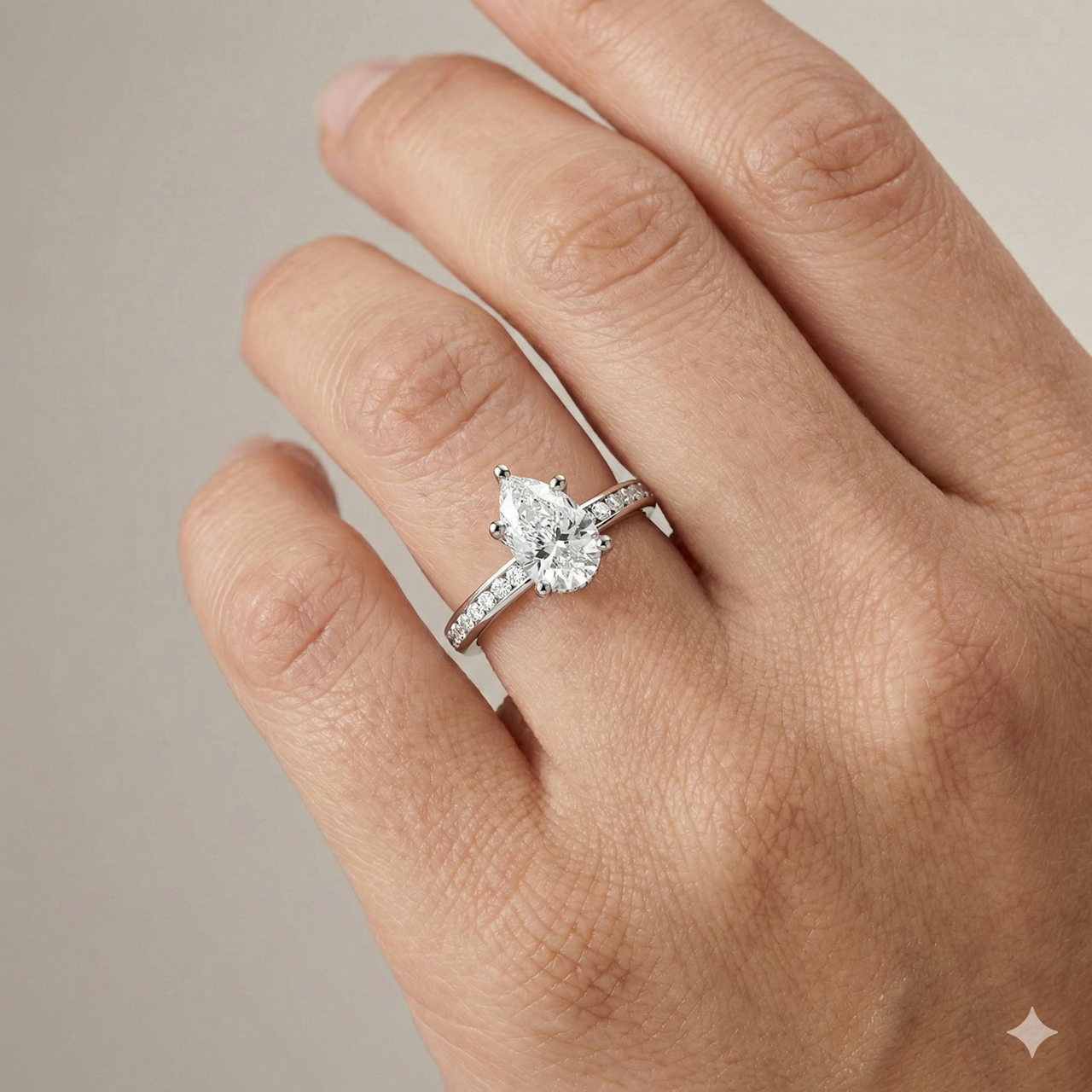 Pear cut diamond engagement ring in 14k white gold with a diamond channel band and cathedral setting on a hand