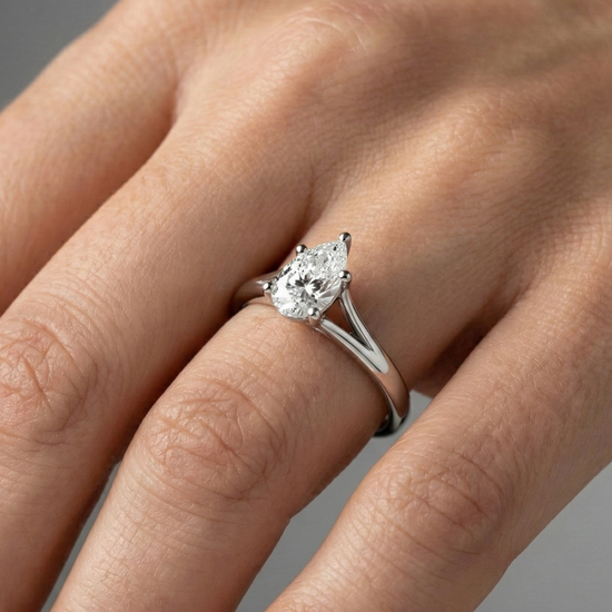 Pear cut diamond engagement ring in 14k white gold with a plain band and split setting on a hand