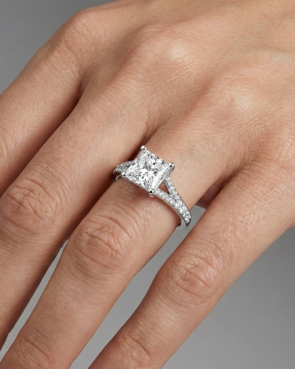 Princess cut diamond engagement ring in 14k white gold with a diamond channel band and split setting on a hand