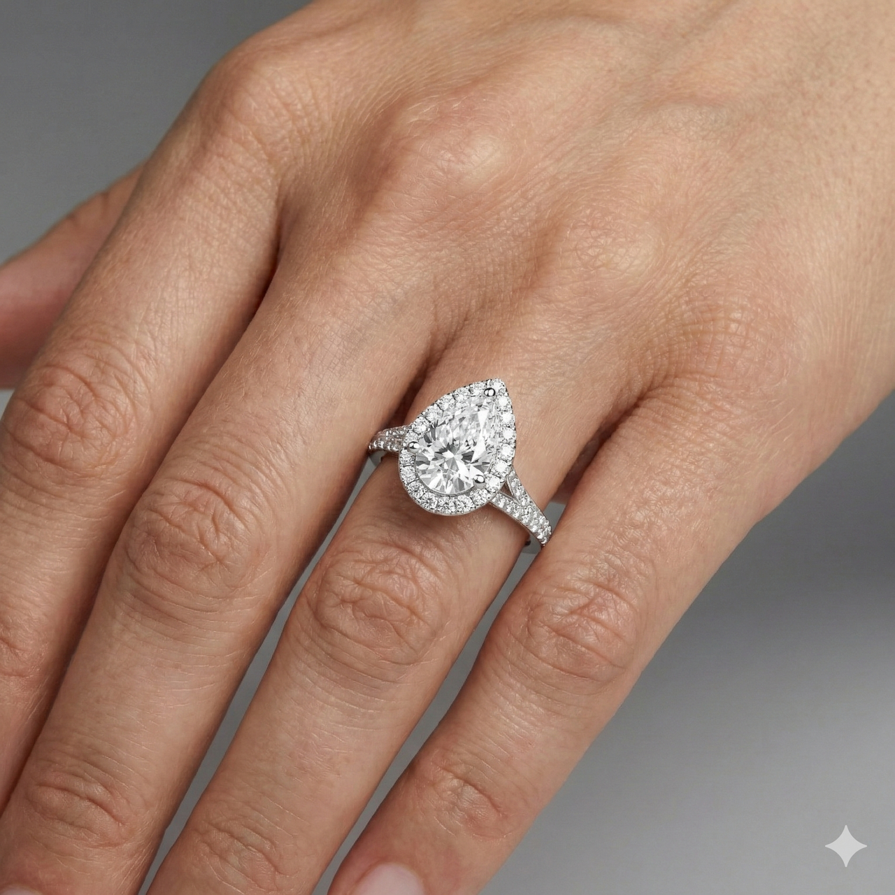 Pear cut diamond engagement ring in 14k white gold with a diamond channel band and split setting on a hand