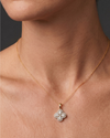 Close-up of a person's neck and collarbone wearing a fine gold chain necklace with a diamond flower pendant featuring pear-shaped stones and a pavé halo.