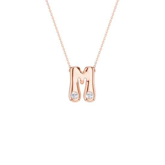 A rose gold initial pendant necklace featuring the letter 'M' with two small clear gemstones at its base, suspended from a delicate rose gold chain against a solid white background.